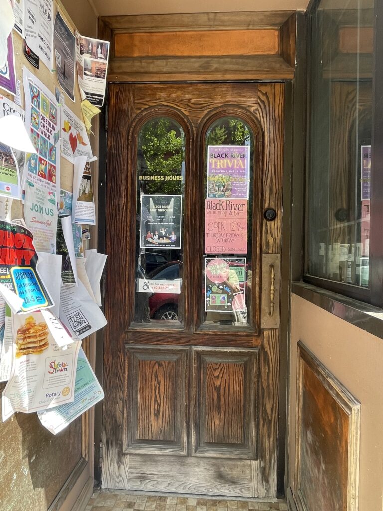 This is a photo of the front door of the Black Rive Cafe in Oberlin, adorned with posters advertising community events, such as Karaoke Night and the Baby Takeover event.