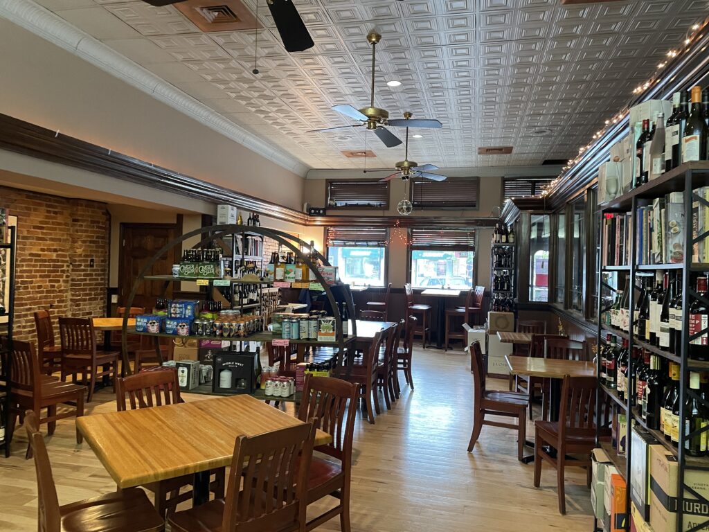 This is the interior of Black Rive Cafe in Oberlin, owned by Joe Waltzer. There are tables and chairs, shelves of wine and books, and lots of open space for patrons.