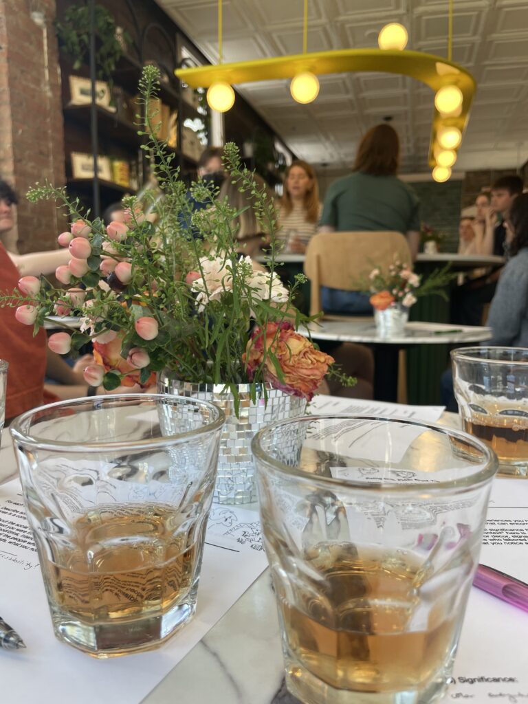 Two glasses of FAUX Rosé sit on a table with a centerpiece of flowers in Verbena.