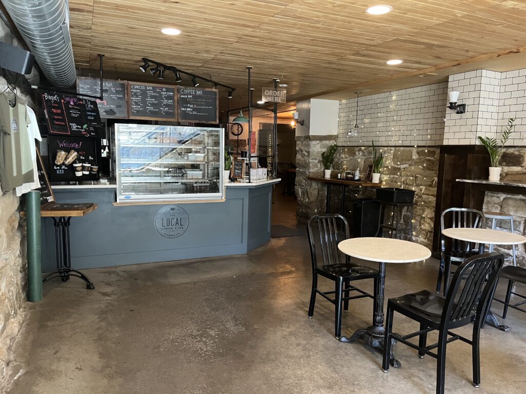 An empty coffee shop before opening with most lights off and an empty bakery case.
