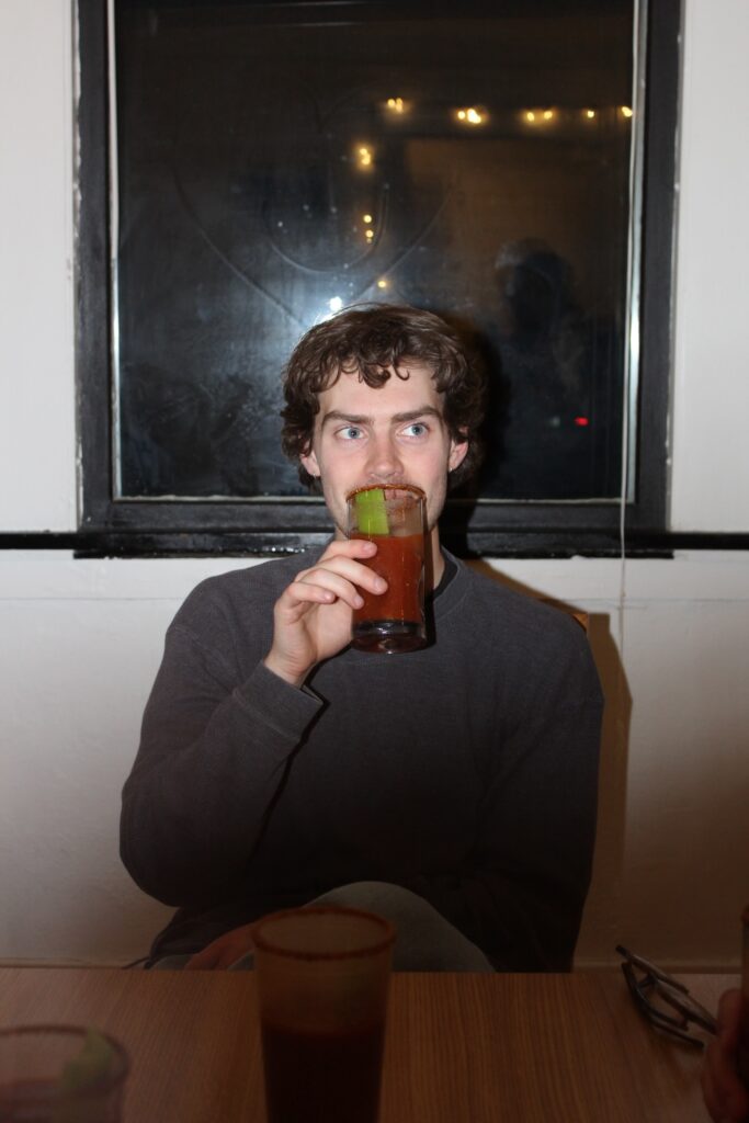 Trevor Balsley sips his bloody mary in front of a window.
