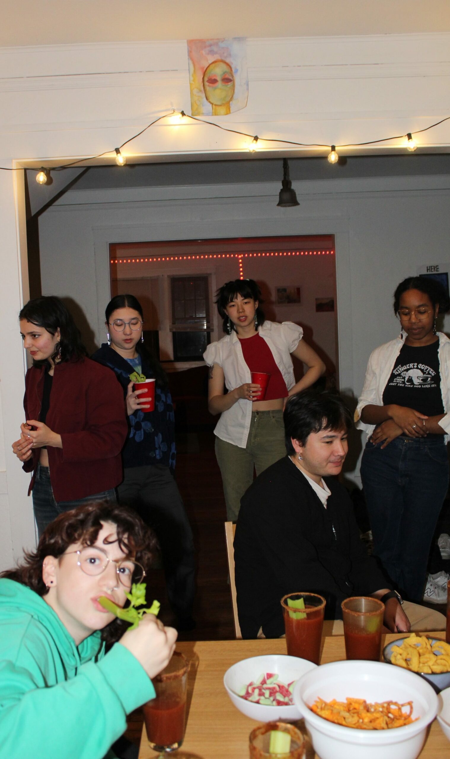 At a small bloody mary gathering, someone takes a bite of the celery in their drink.