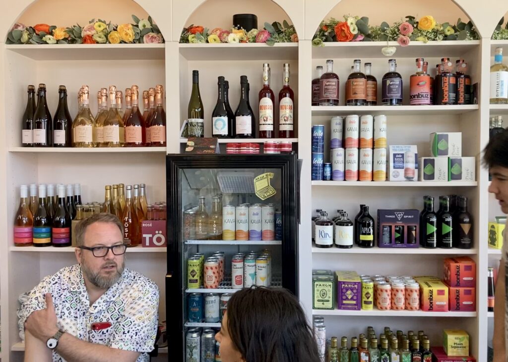 Verbena’s wall of retail products houses bright, colorful cans and bottles on shelves and in a mini fridge with a clear door.