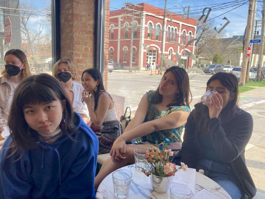 Two tables of 3 students each sit at tables in Verbena, listening to a speaker off camera and sampling glasses of NA product.
