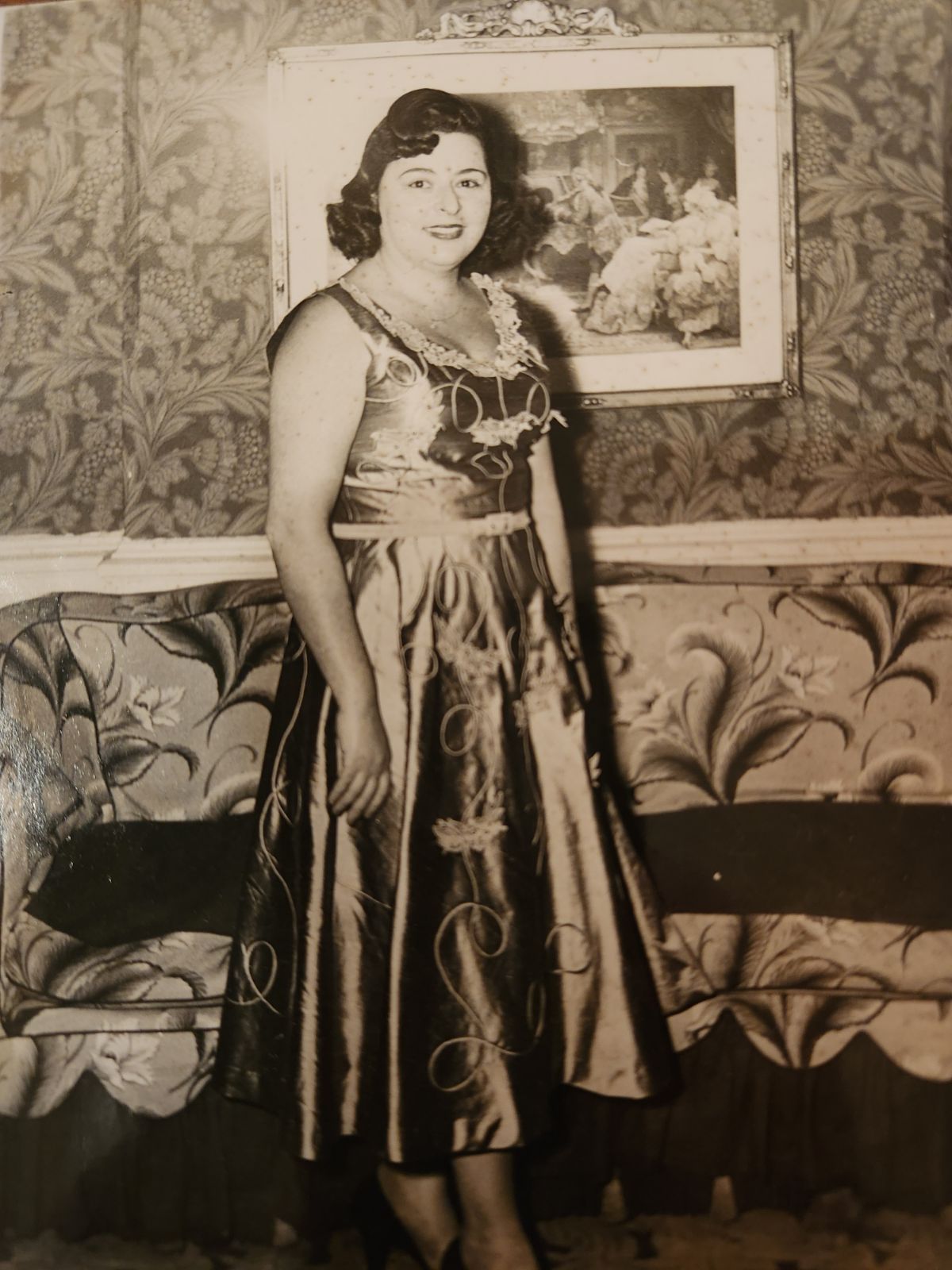 Black and white photo of a woman in front of a painting wearing a long dress